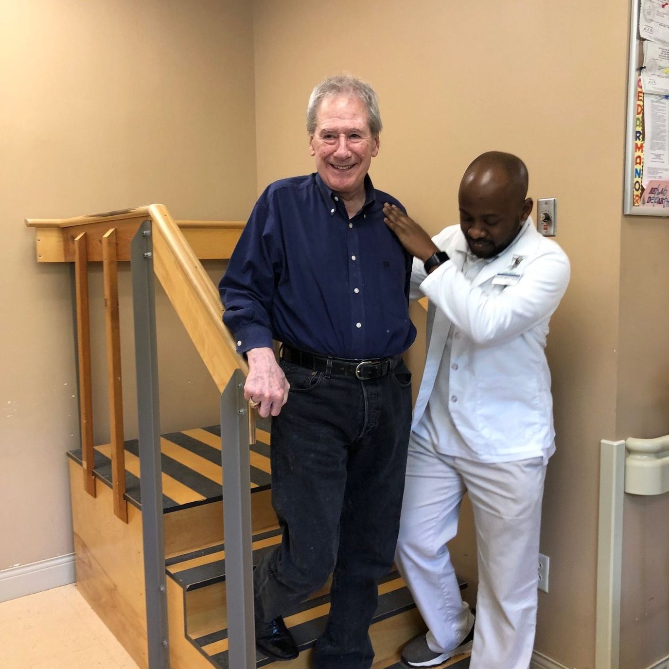Staff assisting a resident on stairs inside the facility
