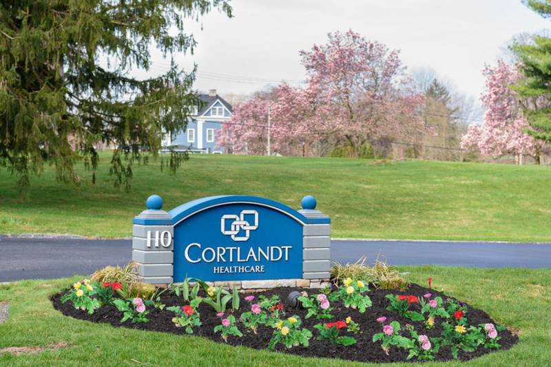Exterior sign of Cortlandt Healthcare with blooming flowers