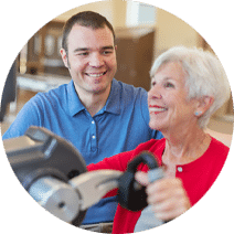 Reedwood Post Acute, Nursing Home in Portland, OR — Senior resident exercising with staff assistance in a fitness center