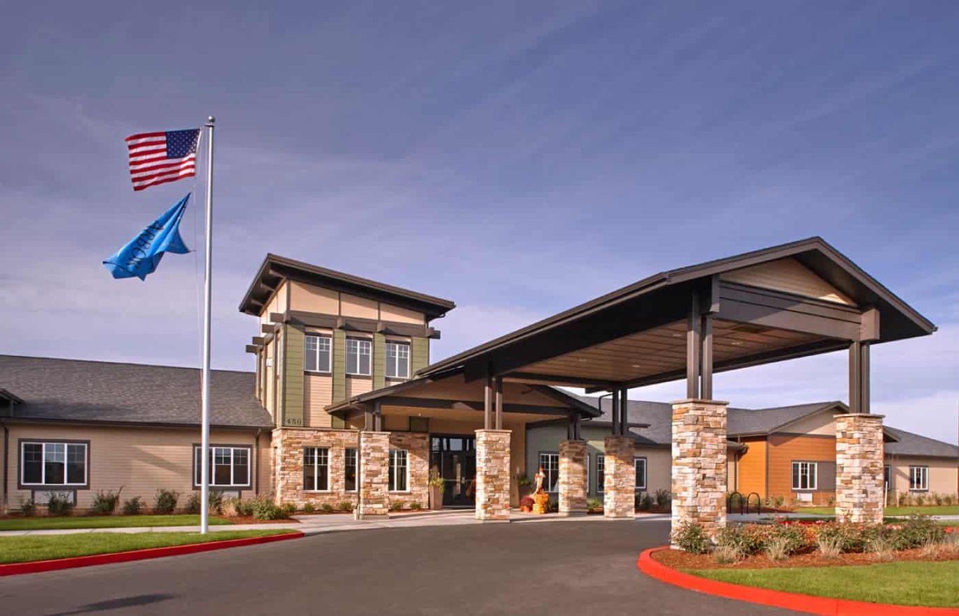 Front entrance of a senior living facility with flagpoles