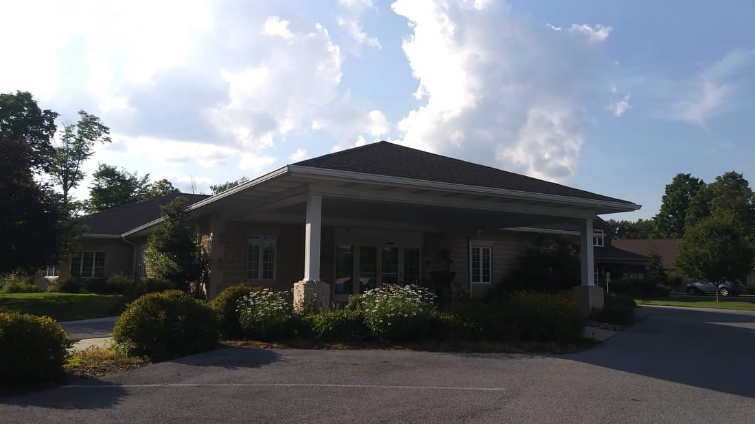 Entrance of a senior living facility surrounded by greenery