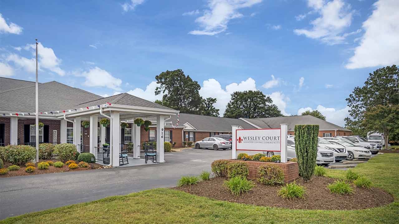 Exterior view of Wesley Court Assisted Living Community with vehicles