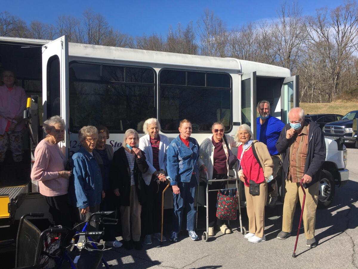 Residents boarding a facility shuttle bus outdoors