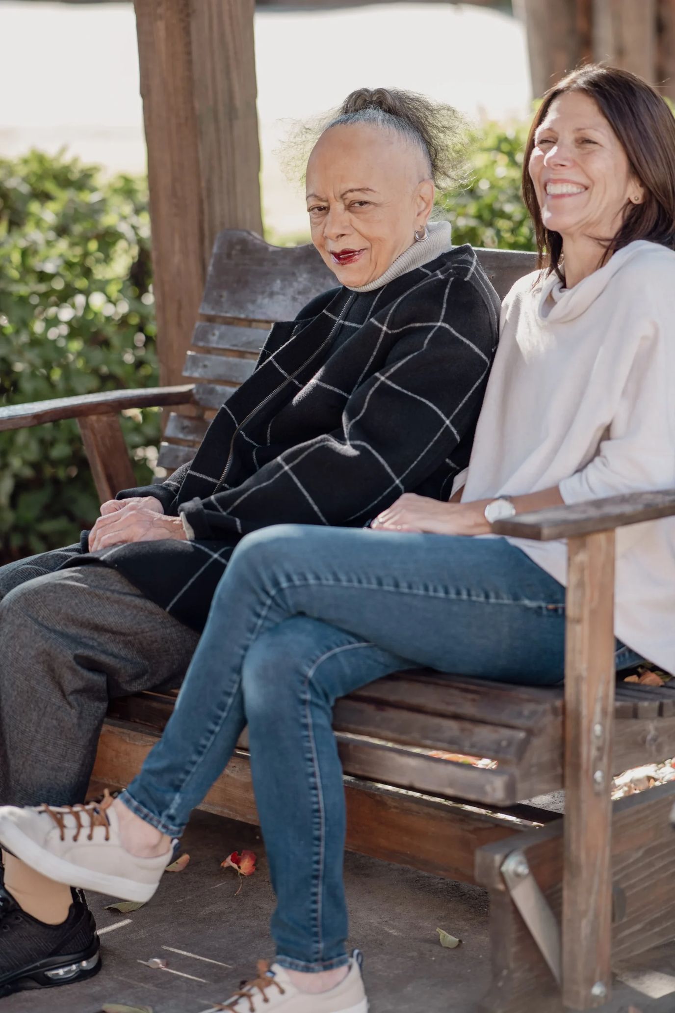 Two women enjoying a moment on a bench in a garden