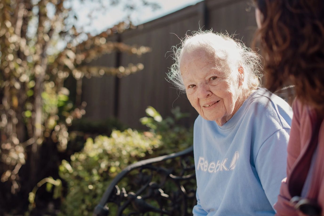 An elderly woman smiling in a garden