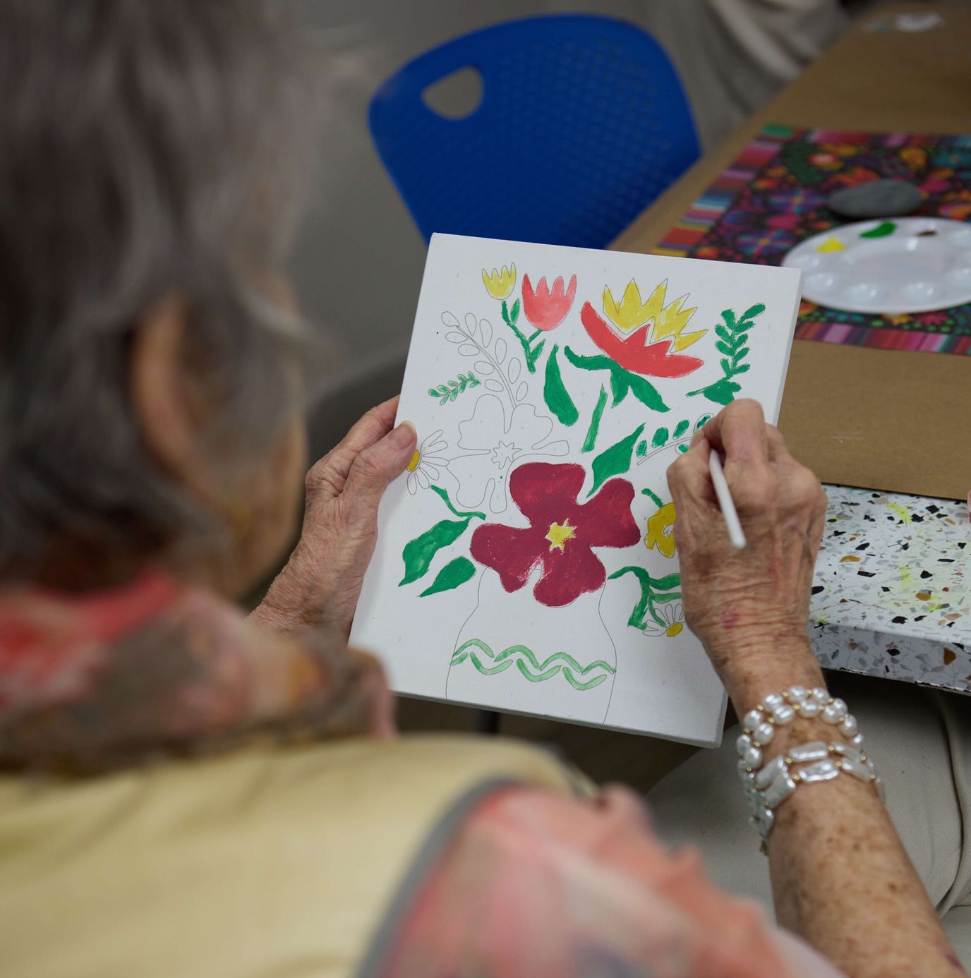 Resident painting a floral design in an activity