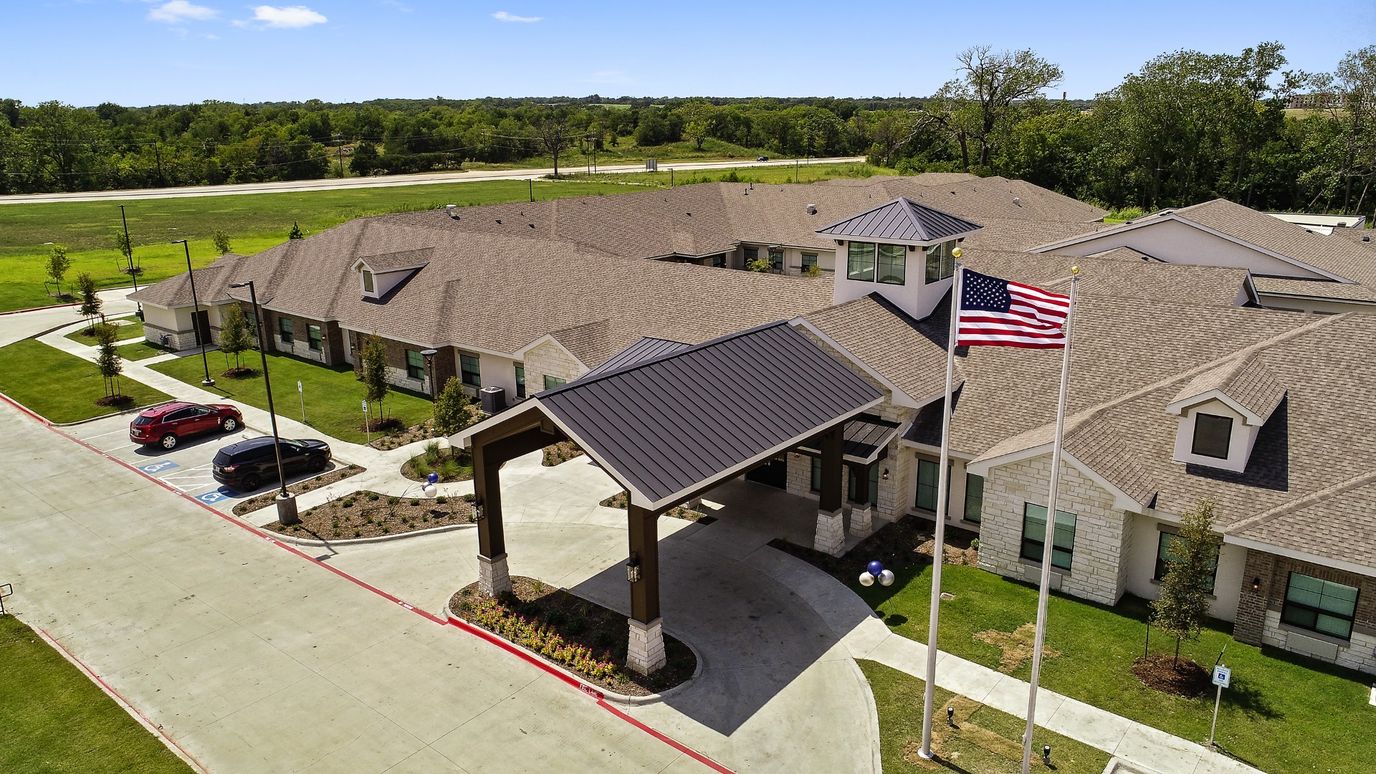 Aerial view of a senior living facility entrance with flag