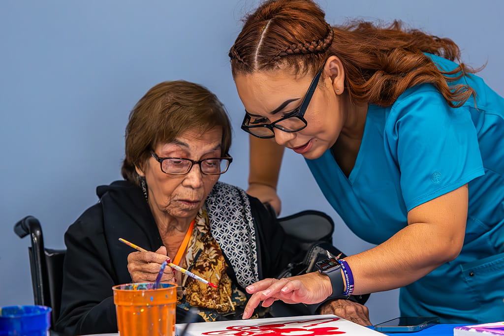 Caregiver assisting a resident with painting activity