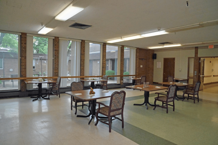 Dining area with tables and chairs, bright windows