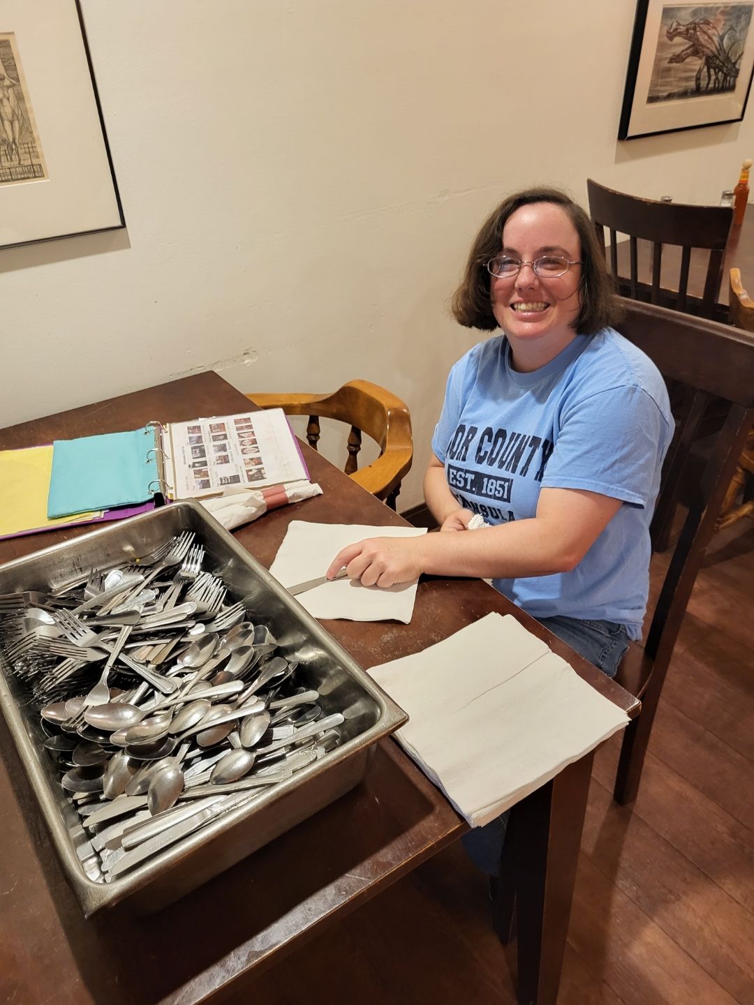 A staff member preparing utensils in a dining area