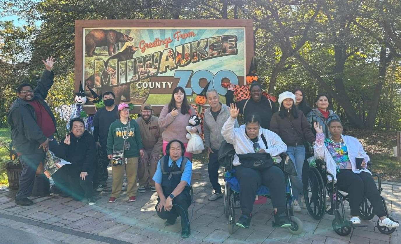 Group photo of residents outside the Milwaukee County Zoo sign