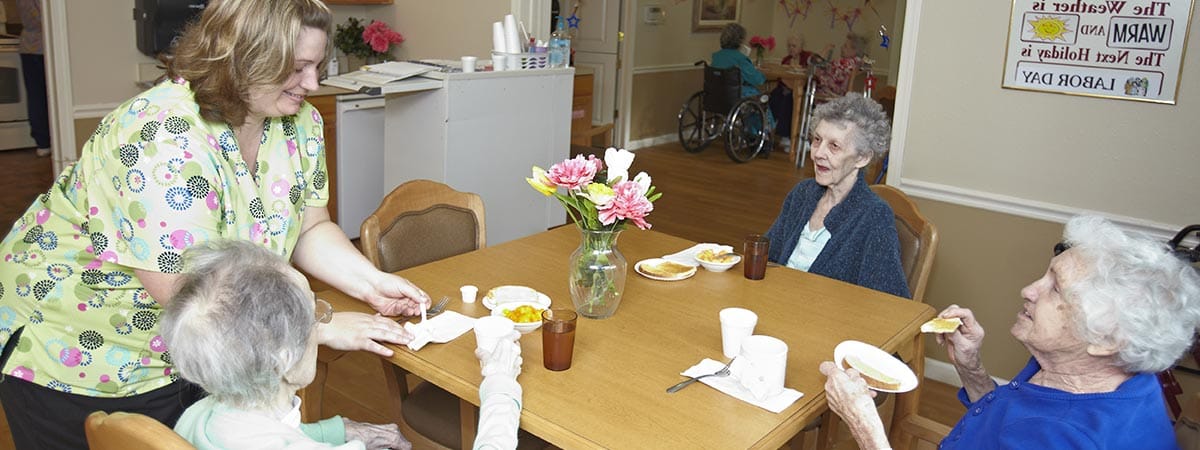 Residents enjoying lunch with staff in a dining area