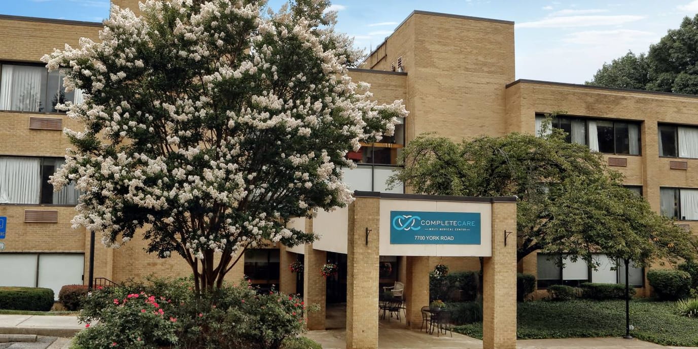 Exterior view of Complete Care facility with flowering trees