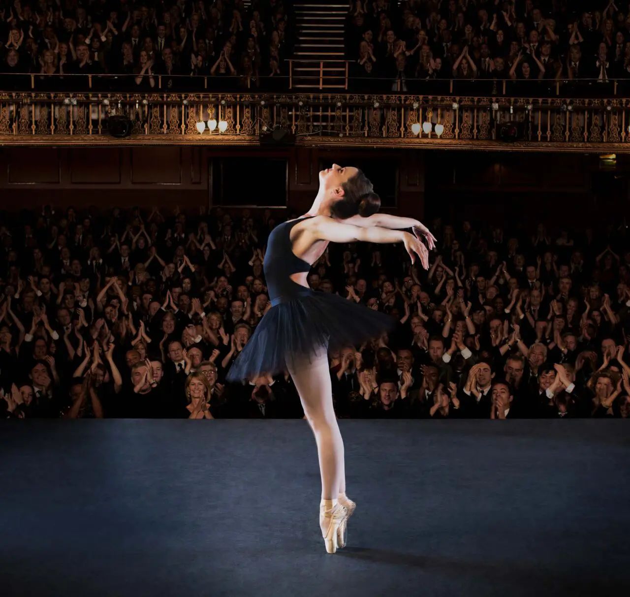A ballerina performing on stage in front of a large audience