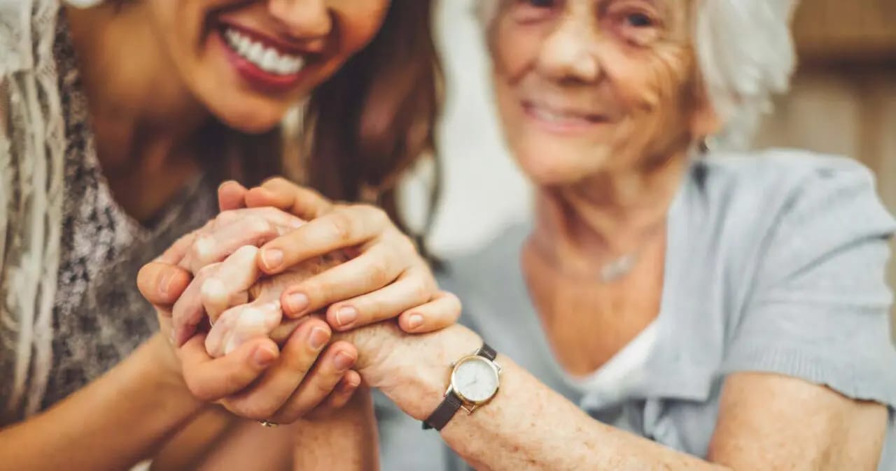 A caregiver holding hands with an elderly resident