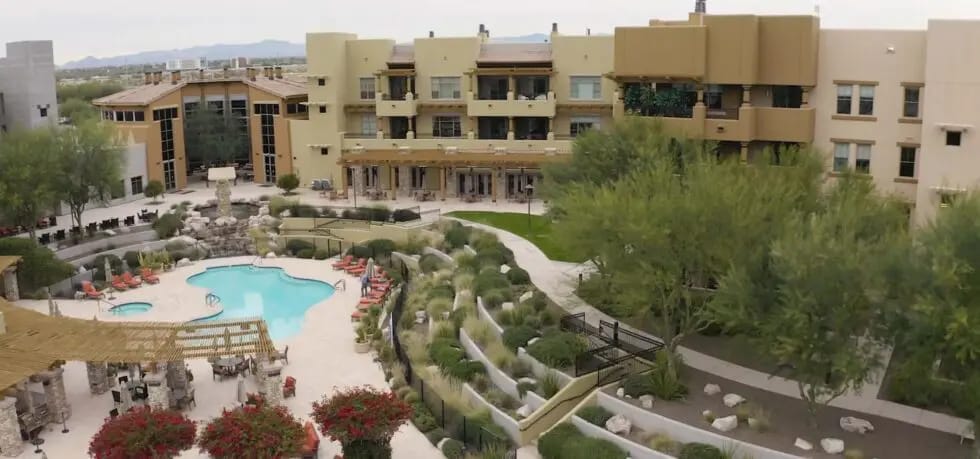 Aerial view of a senior living facility with a pool and gardens