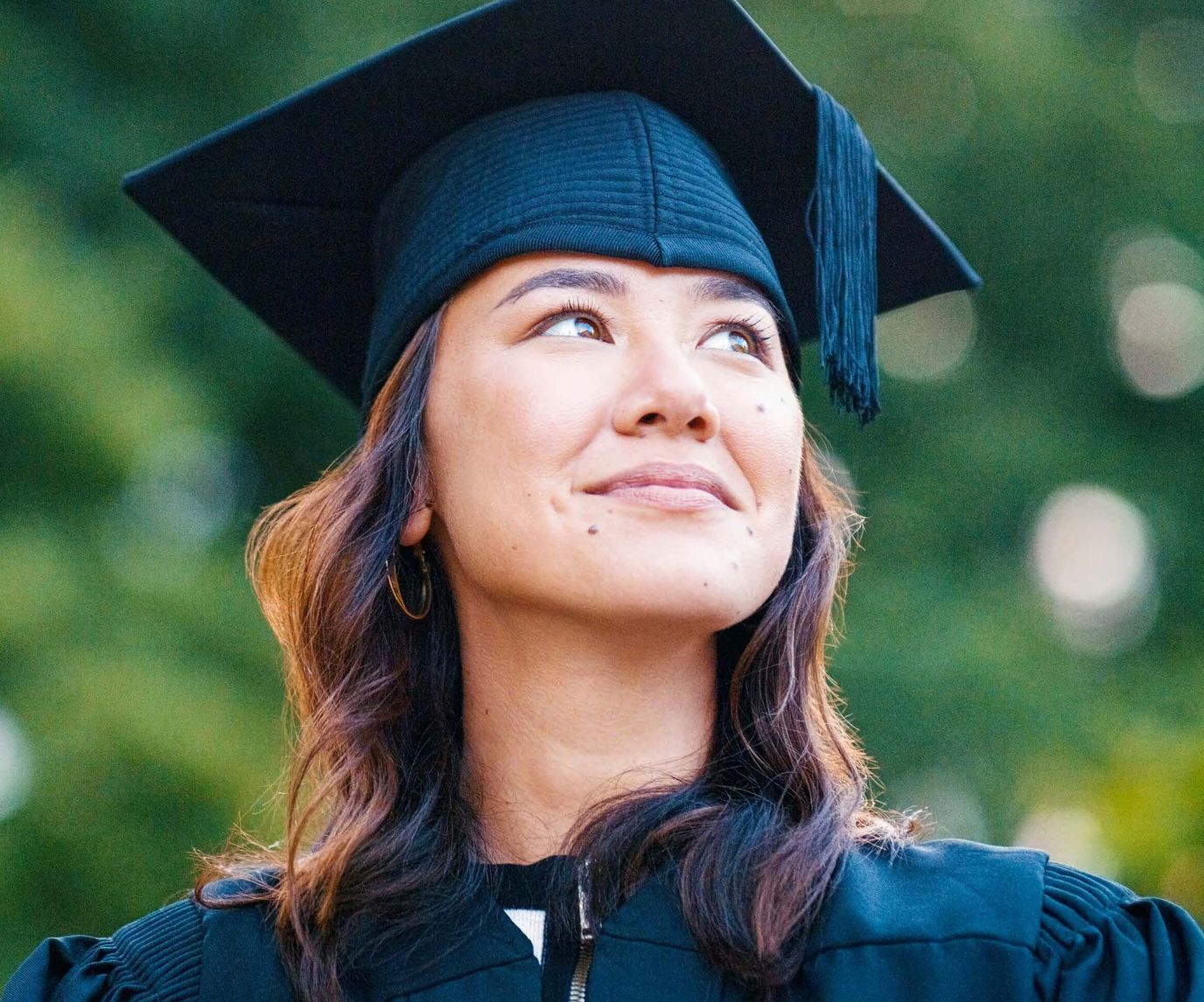 A graduate in cap and gown with a thoughtful expression