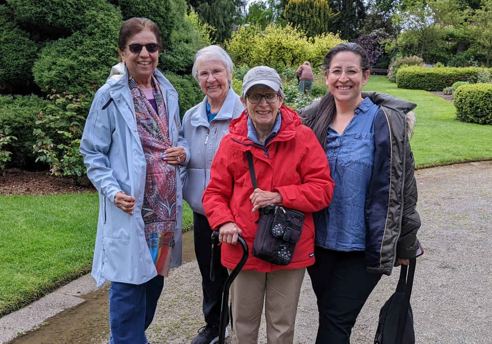 Group of four women enjoying time outside in a garden.
