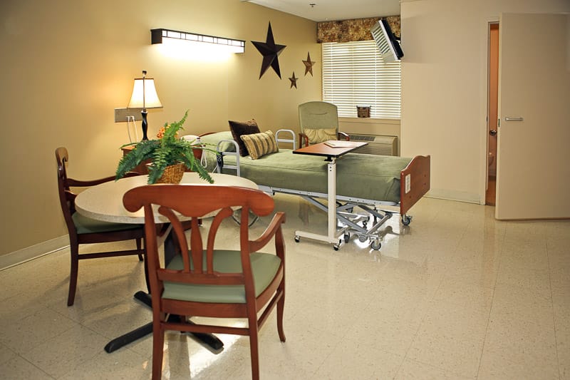 A well-furnished resident room with a bed and table