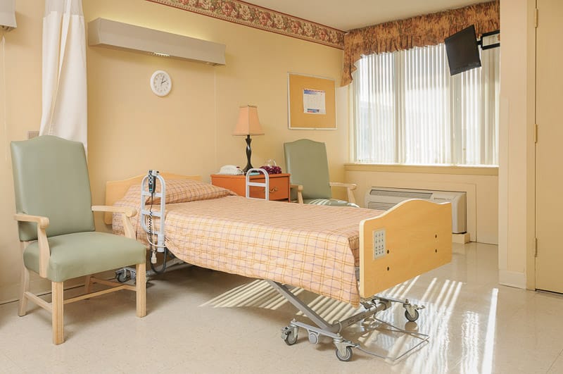 A single resident room with bed and chairs