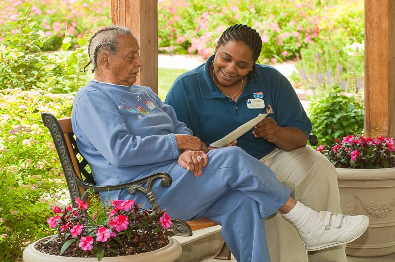 A staff member reading to a resident in a garden