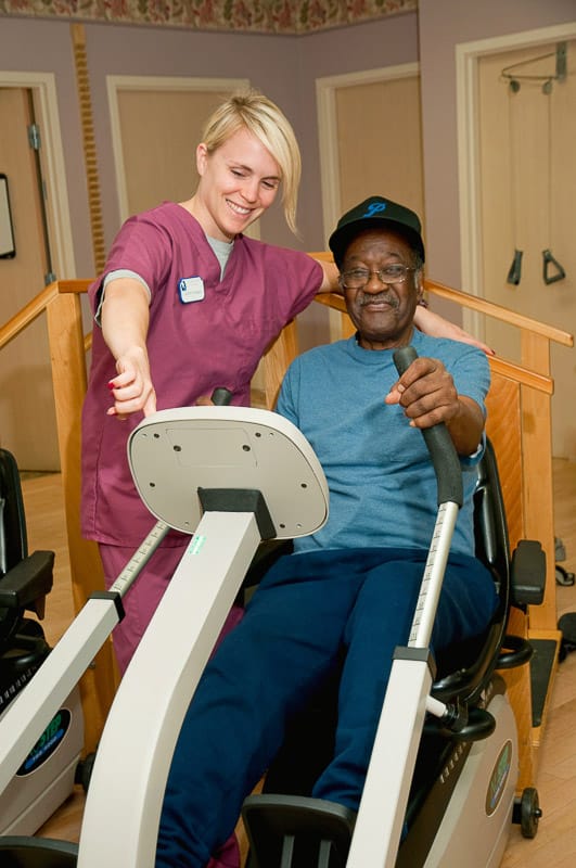 Resident exercising with a staff member in a gym