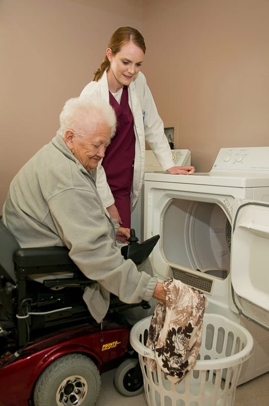 Resident and staff member working together on laundry