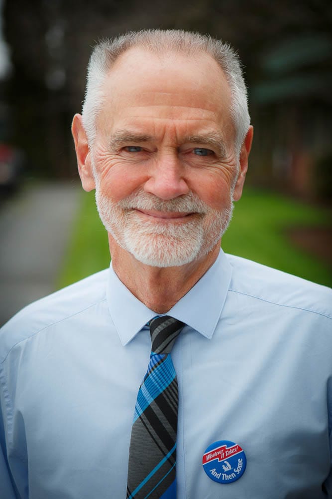 Smiling elderly man in a blue shirt with a badge