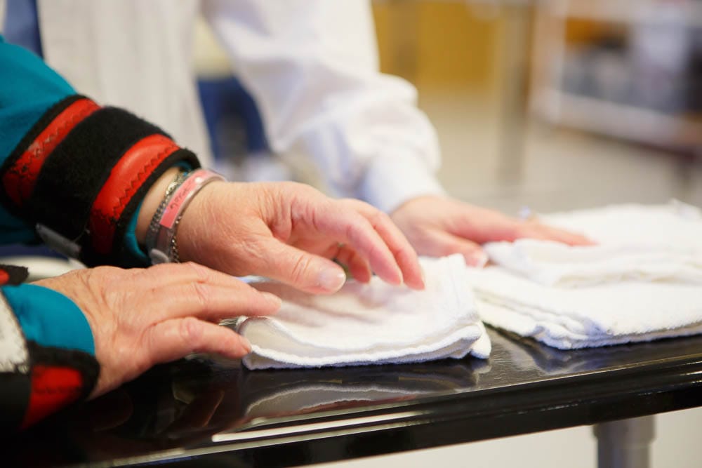 Hands of staff and resident folding towels