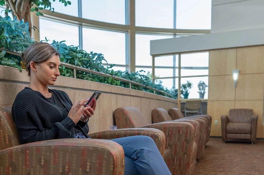 A young woman using her phone in a common area