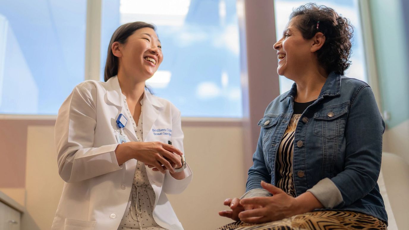 A staff member laughing with a resident in an interior space