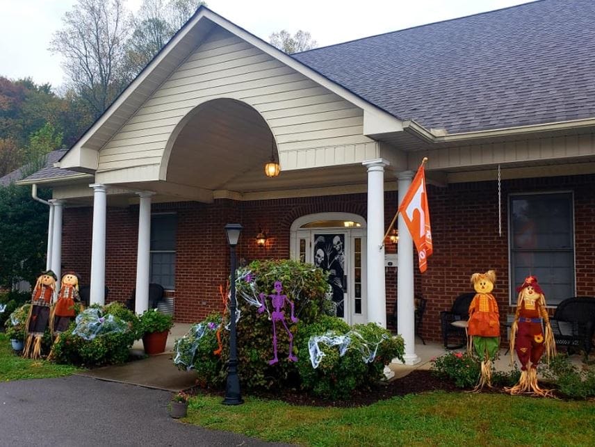 Front entrance of Heritage Assisted Living decorated for fall with scarecrows and Halloween decor.