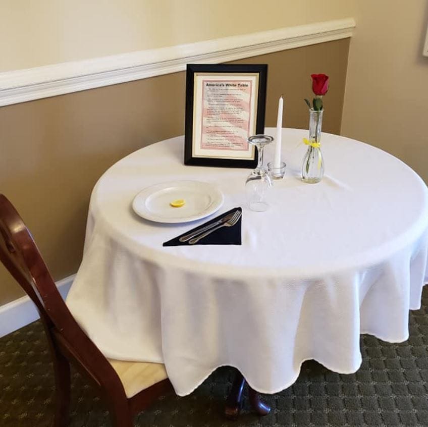 Table set for dining with a candle, rose, and menu