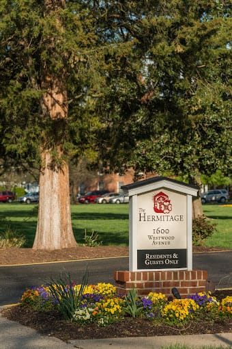 The entrance sign of Hermitage Richmond surrounded by colorful flowers.