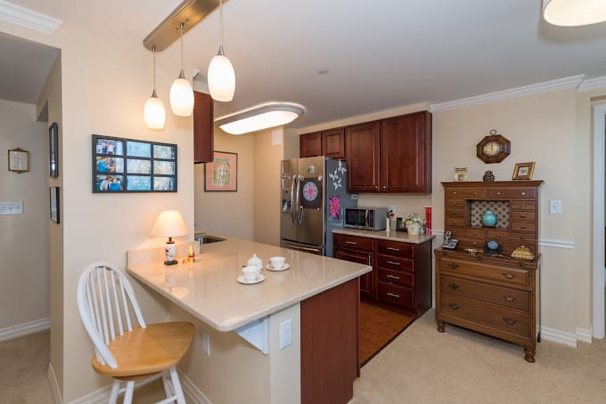 Modern kitchen in a senior living facility with wooden cabinets and dining area.