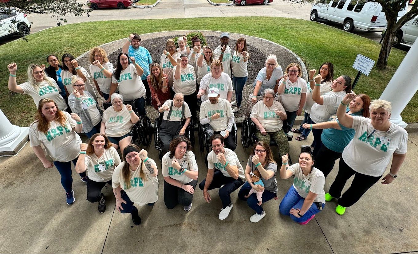 Group of residents and staff at Heritage Center showing 'hope' signs