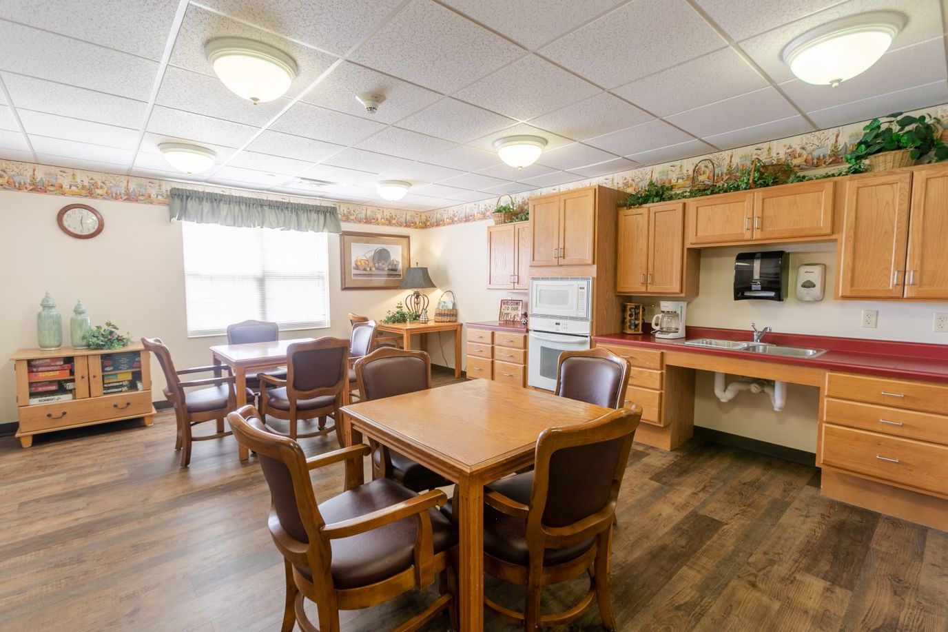 Spacious community room with wooden dining tables and a kitchenette.