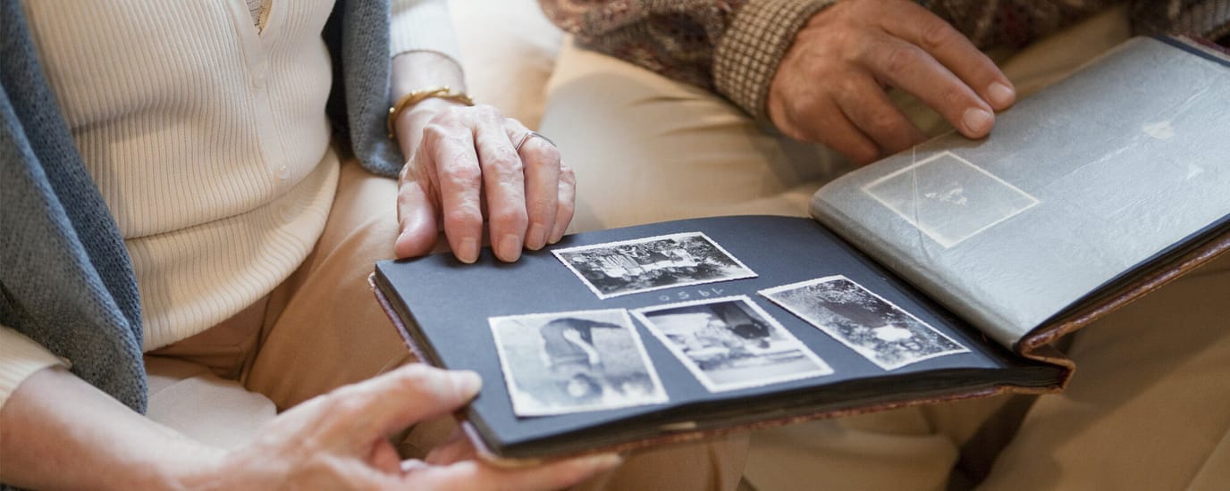 Two hands holding an old photo album with black and white pictures