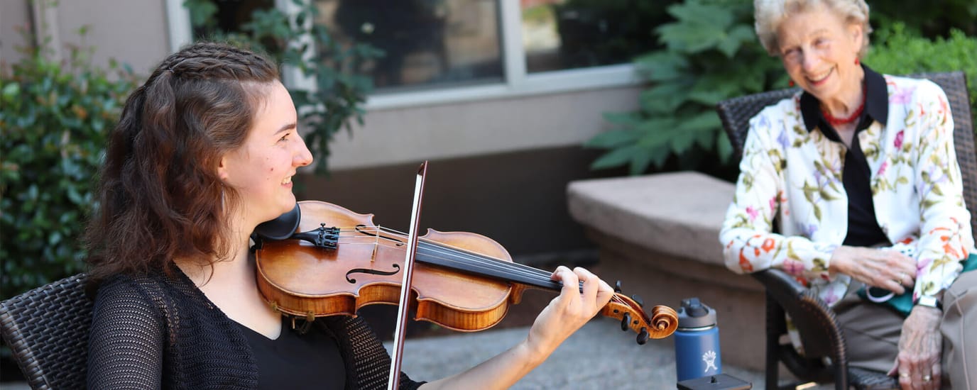 Resident enjoying a violin performance outdoors