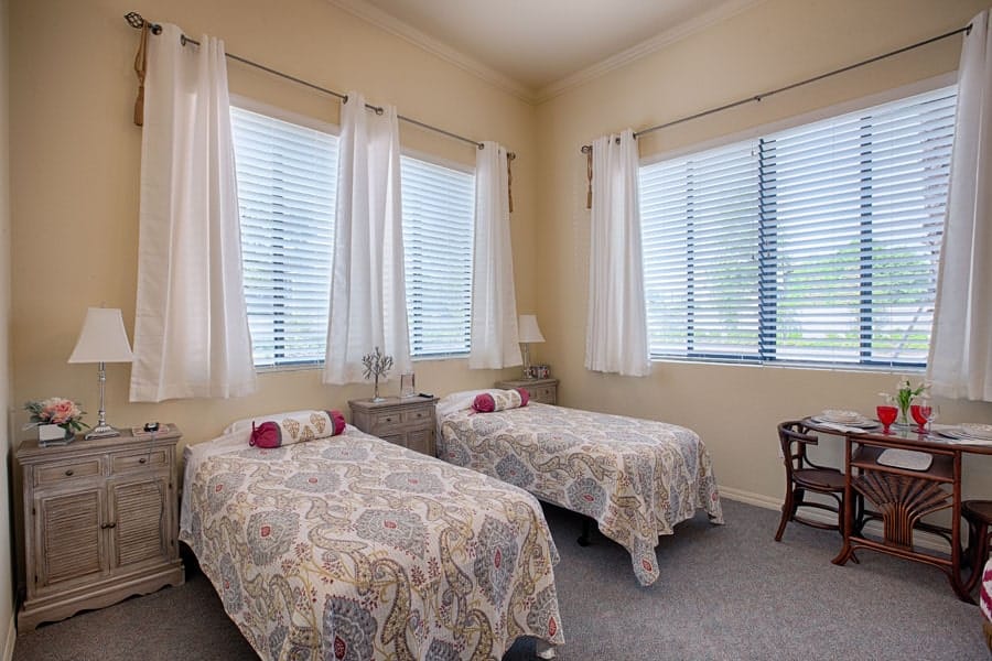 Cozy resident room with two beds and windows.