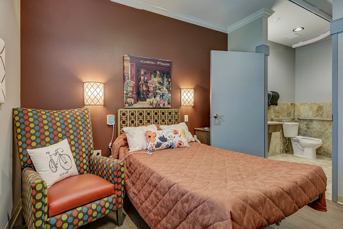 A cozy bedroom with a bed, polka dot chair, and artwork