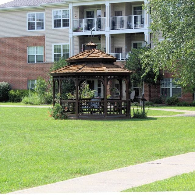 Wooden gazebo surrounded by greenery near residential building