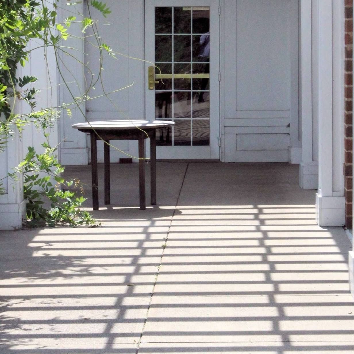 Table near entrance with shadows on the ground.