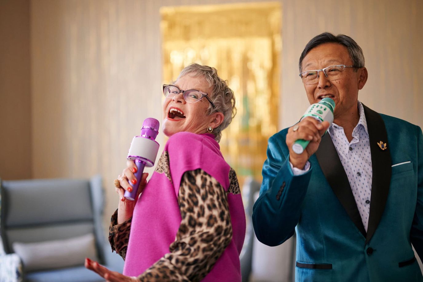 Two residents singing karaoke in a lively activity room