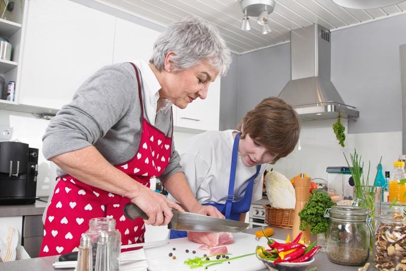 Senior cooking with a youth in a kitchen