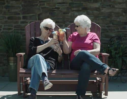 Two women enjoying drinks on a bench