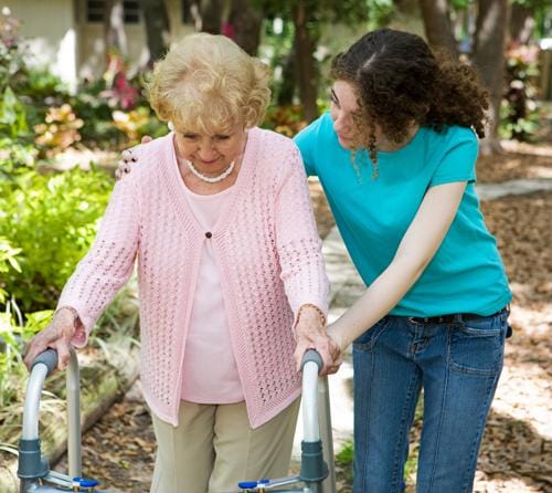 A caregiver assisting a senior woman outdoors