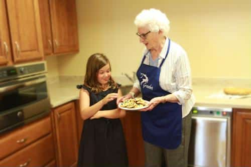 Senior resident baking cookies with a child in a kitchen
