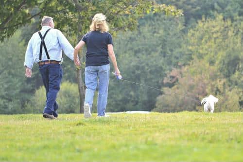 Couple walking a dog in a green outdoor park