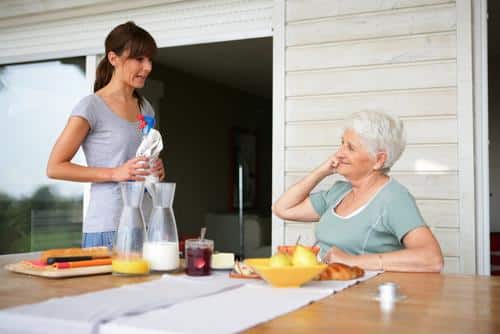 Caregiver serving a meal to a senior woman